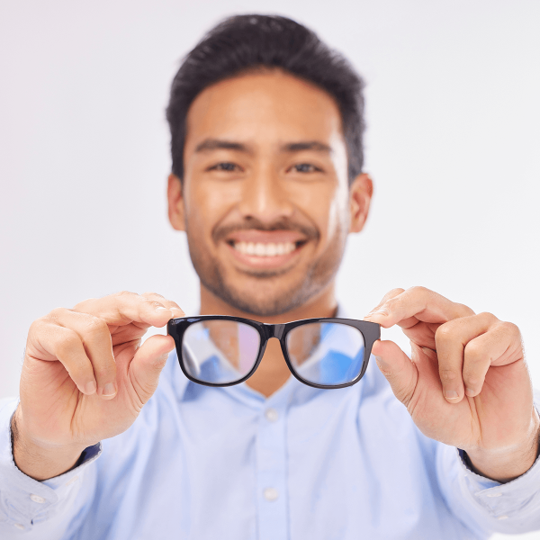 Homme tenant ses lunettes devant lui